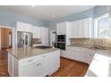 Open kitchen featuring white cabinets, granite countertops, stainless steel appliances, tile backsplash, hardwood floors and gas cooktop island at 430 Federal Rd, Benson, NC 27504