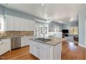 Spacious kitchen with island, white cabinets, stainless appliances, and breakfast area with large windows for natural light and hardwood floors at 430 Federal Rd, Benson, NC 27504