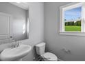 Small half bathroom with white pedestal sink and toilet, and a window overlooking the backyard at 93 Macy Cir, Wendell, NC 27591