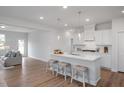 Spacious kitchen with marble counters, white cabinets and island with bar seating, open to living room at 18 Fairwinds Drive Dr, Lillington, NC 27546