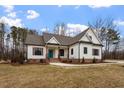 Modern farmhouse exterior with white siding, gray roof, and landscaping at 195 Daniel Ridge Ln, Roxboro, NC 27574