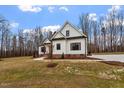 White farmhouse with gray roof, brick base, and landscaping at 195 Daniel Ridge Ln, Roxboro, NC 27574