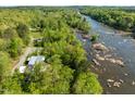 Aerial view of a modern solar paneled home surrounded by lush greenery and a scenic river at 196 Paces Mill Trl, Pittsboro, NC 27312