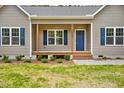 Inviting front porch with wooden pillars, a blue front door, and lovely landscaping at 2857 Greenbrook Dr, Wendell, NC 27591