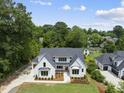 Aerial view of a white painted brick two-story home with a well-manicured lawn and a dark roof at 5820 Shawood Dr, Raleigh, NC 27609