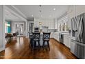 Bright, airy kitchen featuring white cabinets, stainless steel appliances, island with seating, and hardwood floors at 1000 Norris St, Raleigh, NC 27604