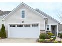 Close up view of a charming one story home with a two car garage, light siding, and landscaped front yard at 125 Canary Ct. Ct, Raleigh, NC 27610