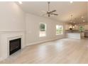 Bright living room featuring light wood floors, a ceiling fan, a fireplace, and views of the kitchen at 1701 Drayton Hall Ln, Sanford, NC 27330