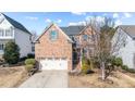 Charming two-story brick home featuring an attached two-car garage, established landscaping, and mature tree at 912 Jewel Stone Ln, Morrisville, NC 27560