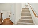 Carpeted staircase with wooden banister leading to the upper level at 219 Broadgait Brae Rd, Cary, NC 27519