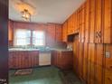 Retro kitchen with wood cabinets, white appliances, and green flooring at 301 N Ellis Ave, Dunn, NC 28334