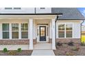 Inviting front porch featuring classic white columns, brick accents and a black front door at 66 Tennyson Dr, Garner, NC 27529