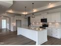 A modern kitchen featuring white cabinets, a large island, and stainless steel appliances at 134 Oban Dr, Homesite 133, Sanford, NC 27330