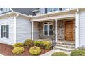 Stone front porch with wooden door and black railing at 1513 Hoke Landing Ln, Raleigh, NC 27603