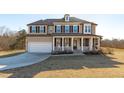 Charming two-story home featuring a welcoming front porch with rocking chairs and a well-manicured lawn at 189 Sunrise Ridge Dr, Willow Springs, NC 27592