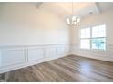 Elegant dining room with hardwood floors, wainscoting, coffered ceilings, and a modern chandelier at 223 Johnson Ridge Way, Four Oaks, NC 27524