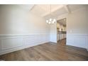 Dining room with hardwood flooring, wainscoting, coffered ceilings, chandelier, and open to the kitchen at 236 Johnson Ridge Way, Four Oaks, NC 27524