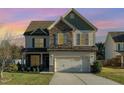 Charming two-story home with a mix of stone and siding, well-manicured lawn, and an attached two-car garage at 2407 Cattail Pond Dr, Zebulon, NC 27597