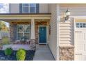 Inviting front porch with stone accents, teal door, and seating area at 2407 Cattail Pond Dr, Zebulon, NC 27597