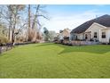 Expansive backyard featuring a lush lawn, a stone-lined patio, and mature trees providing privacy at 347 Country Mill Way, Fuquay Varina, NC 27526