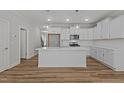 Modern kitchen with stainless steel appliances, large island with quartz countertops, and hardwood floors at 610 Marshskip Way, Rolesville, NC 27587