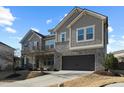 Two-story home with gray siding, stone accents, and a three-car garage at 1819 Capstone Dr, Durham, NC 27713