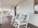 Inviting front porch featuring rocking chairs with stylish floral cushions and a dark stained wood deck at 211 Long Ave, Graham, NC 27253