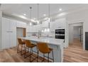 Modern white kitchen featuring an island with bar seating, pendant lighting, and stainless steel appliances at 260 Ellington Rd, Graham, NC 27253