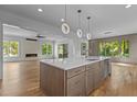 Open-concept kitchen with large island, modern pendant lighting, and view into living room with fireplace at 324 Waldo St, Cary, NC 27511
