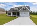 Beautiful new home showcasing a gray exterior, attached garage, and a well-maintained lawn at 6294 River Rd, Fuquay Varina, NC 27526