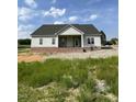 Single story home with brick foundation, covered porch with white columns and ceiling fan with a lawn view at 6294 River Rd, Fuquay Varina, NC 27526