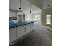 New kitchen features white cabinets, backsplash and island with pendant lighting and natural light through multiple windows at 6294 River Rd, Fuquay Varina, NC 27526