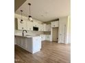 Well-lit kitchen boasts white cabinets, a stylish backsplash, modern fixtures, and wood grain flooring at 6294 River Rd, Fuquay Varina, NC 27526