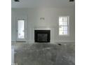 Modern living room features a fireplace with tile surround, white trim and wainscoting with access to the yard at 6294 River Rd, Fuquay Varina, NC 27526