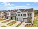 View of new construction townhomes featuring attached garages and manicured lawns at 104 Central Townes Way # 296, Raleigh, NC 27603