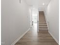 Bright hallway featuring wood floors, white walls, and carpeted stairs leading to the upper level at 148 Fideaux Blvd # 250, Raleigh, NC 27603