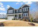 Two-story house, gray siding, stone accents, and a three-car garage at 6217 Adcock Rd, Holly Springs, NC 27540