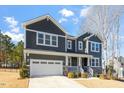 Two-story house with gray siding, stone accents, and a three-car garage at 6217 Adcock Rd, Holly Springs, NC 27540