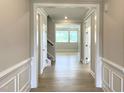 Inviting hallway with wood flooring and classic wainscoting leading to a sunlit living area and staircase at 82 N Stagecoach Dr, Wendell, NC 27591