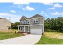 Charming two-story home with a manicured lawn and a long driveway leading to the garage at 139 Grove Township Way, Angier, NC 27501
