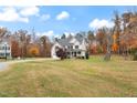 Two-story house with a gray roof and beige siding, a large yard with mature trees and a driveway at 1726 Rapids Ct, Franklinton, NC 27525
