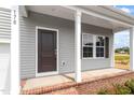 Inviting front porch showcasing gray siding, white columns, and a dark front door at 178 Grove Township Way, Angier, NC 27501