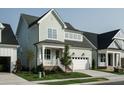 Two-story light green house with white garage door and brick steps at 1813 Bright Lantern Way, Wendell, NC 27591