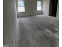 This bedroom features bare walls, concrete floors, and two windows offering ample natural light at 19 E American Marigold Dr # 34, Benson, NC 27504