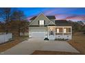 Two-story house with a stone and shingle exterior, front porch, and a two-car garage at dusk at 20 Wes Sandling Rd, Franklinton, NC 27525