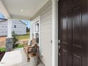 Front porch with a wooden bench, cushions, and dark brown door at 204 E Fountainhead Ln, Garner, NC 27529