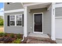 Inviting front entry with a covered porch and black door, and brick steps at 211 Grove Township Way, Angier, NC 27501