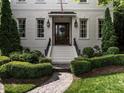 Charming home entrance featuring a decorative door, manicured bushes, and an ornate stone walkway at 2900 Glenanneve Pl, Raleigh, NC 27608