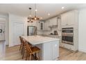 Bright kitchen boasts a large island, stainless steel appliances, white cabinetry, and modern pendant lighting at 40 Ironwood Blvd, Youngsville, NC 27596