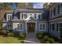 Beautiful gray home featuring a covered front entry, stone steps, mature landscaping, and a welcoming facade at 4201 Henderson Pl, Pittsboro, NC 27312